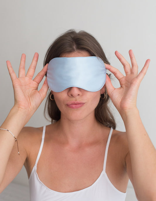 Femme portant un masque de nuit en soie de couleur bleue pale