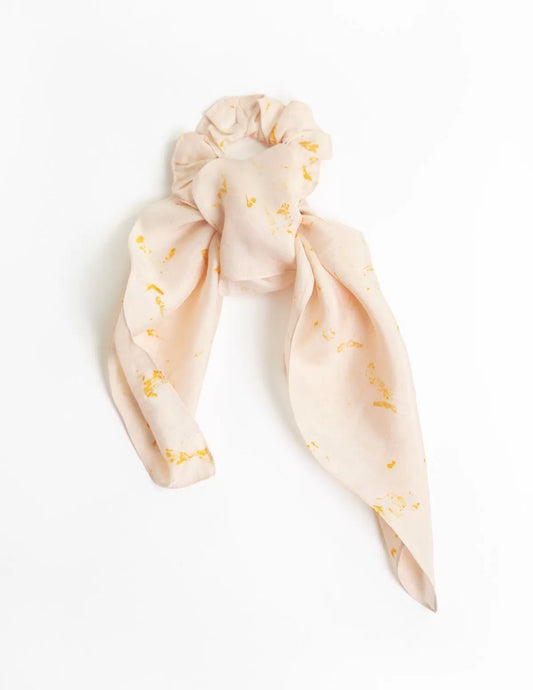 Chouchou-foulard en soie porté sur chignon devant la mer, modèle Colibri, rosé