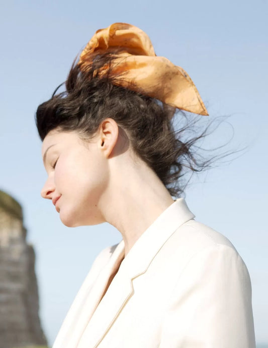 Chouchou-foulard orangé en soie biologique cruelty free, porté dans le vent marin