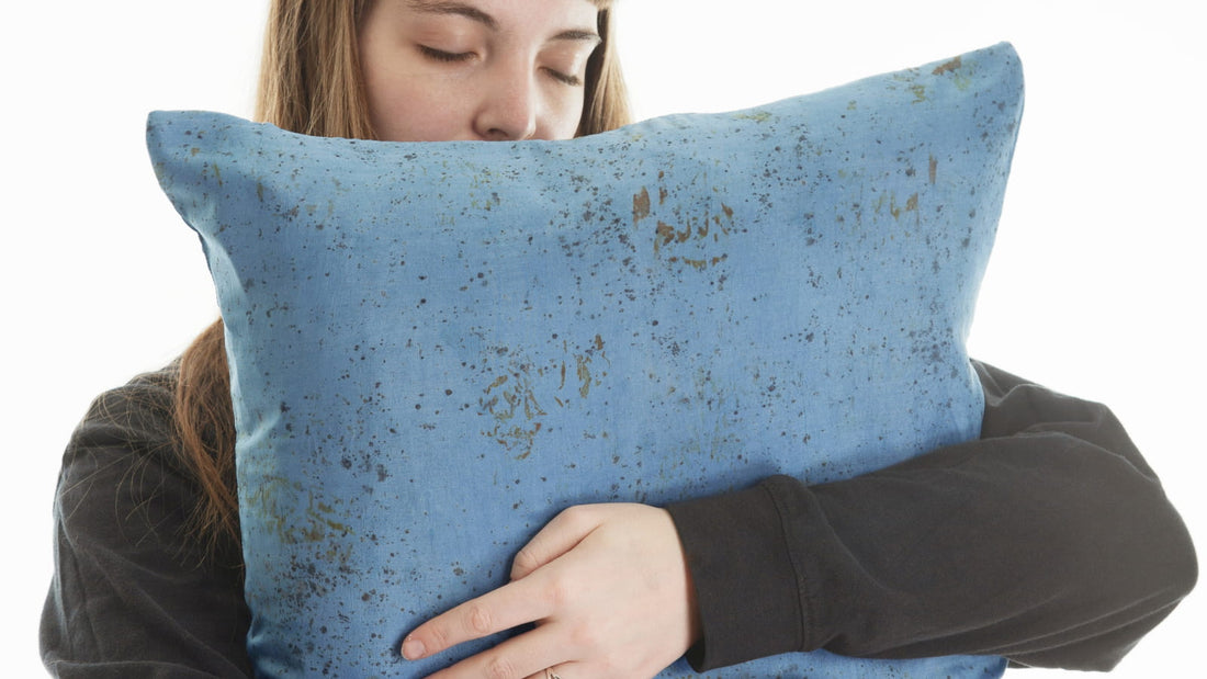 Jeune femme entourant un grand oreiller en soie bleue de ses bras