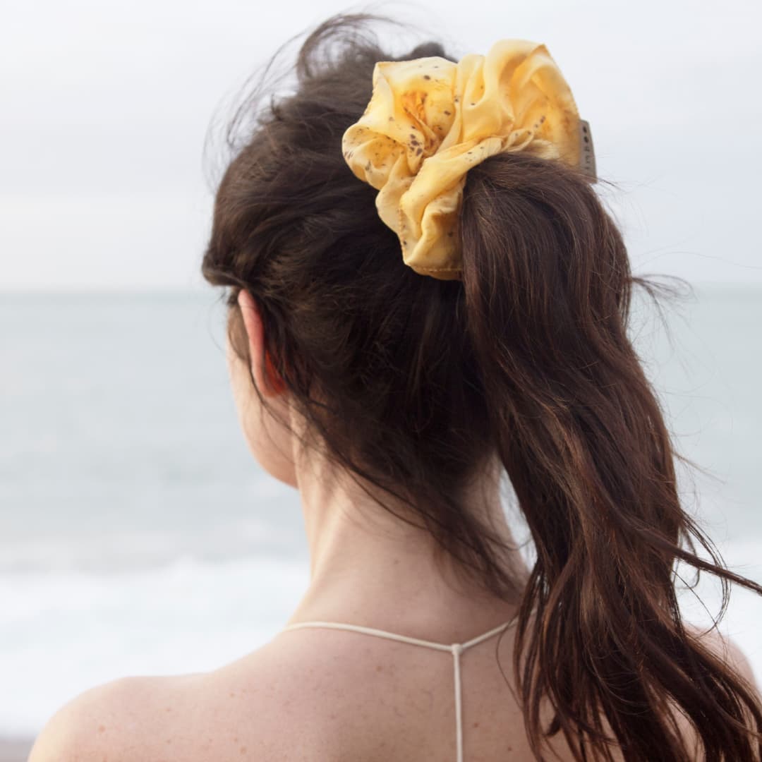 Douceur et bienfaits de la soie sur les cheveux avec ce chouchou en soie bio sur femme regardant l'océan