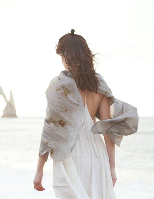 Femme marchant sur la plage et portant une longue écharpe de soie sur ses épaules 