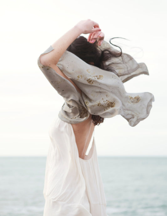 Femme marchant sur la plage et portant une longue écharpe de soie sur ses épaules