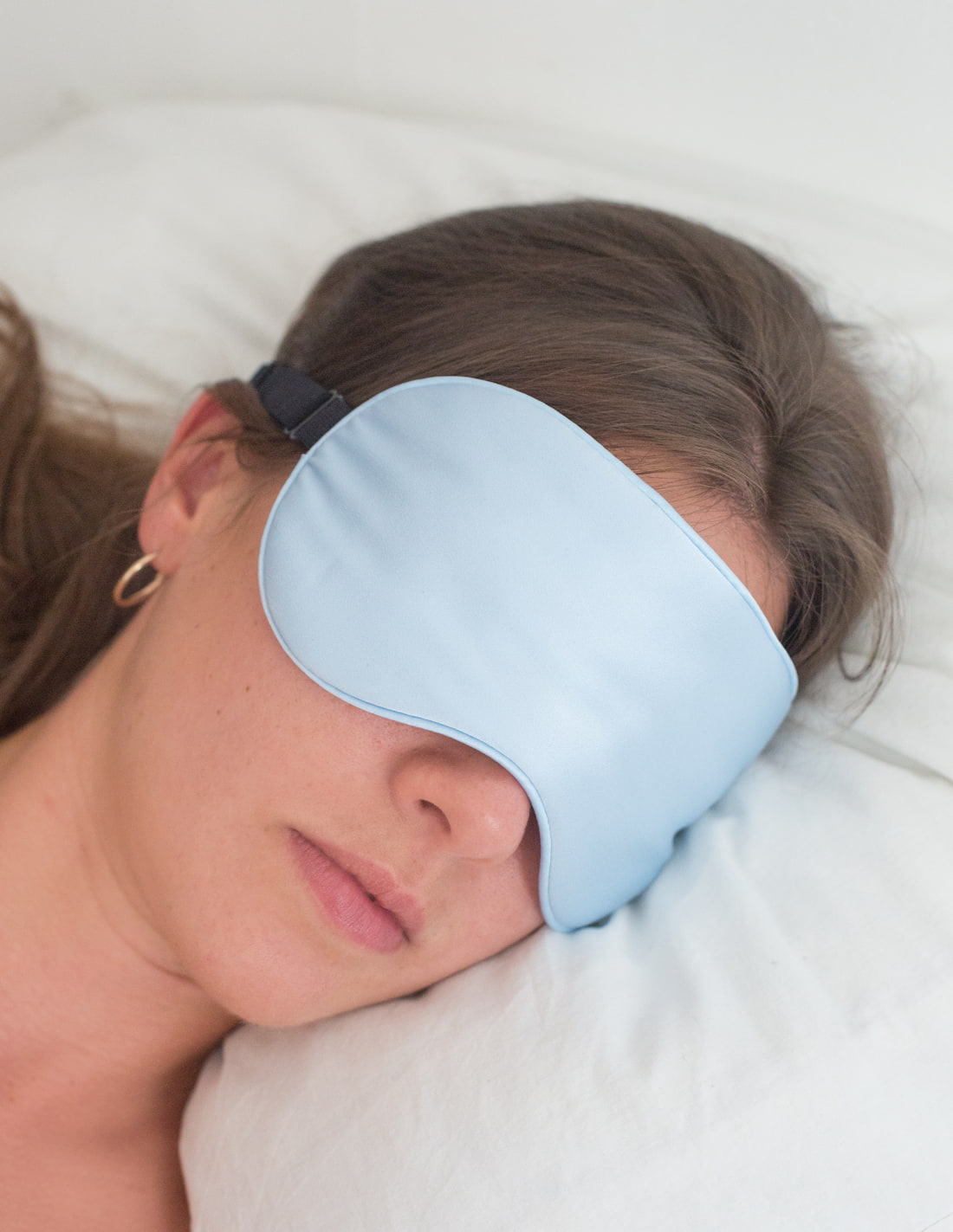 Femme portant un masque de nuit en soie de couleur bleue pale