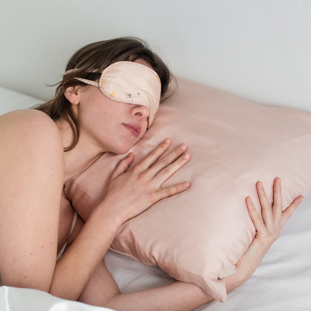 Femme dormant sur une taie d'oreiller en soie et portant un masque de nuit en soie de couleur assortie