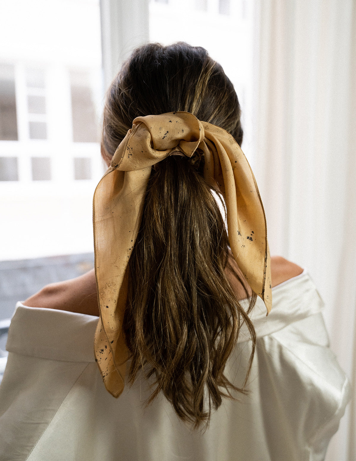 Vue de détail sur le noeud d'un chouchou-foulard en soie élégant, modèle Ananda