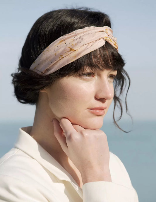 Serre-tête en soie biologique rose, porté par une femme devant la mer