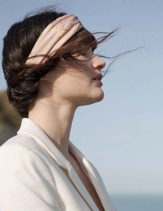 Serre-tête en soie biologique rose, porté par une femme devant la mer